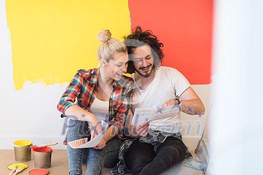 Happy young couple relaxing after painting a room in their new house on the floor Happy young couple relaxing after painting a room in their new house on the floor