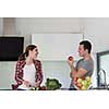 Young handsome couple in the kitchen  beautiful woman preparing a salad while the man eating an apple