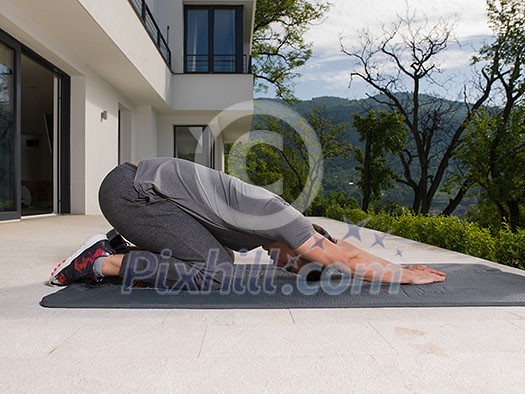 young handsome man doing morning yoga exercises in front of his luxury home villa young handsome man doing morning yoga exercises in front of his luxury home villa