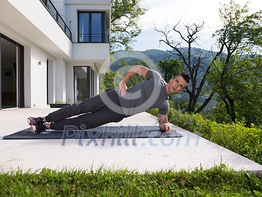 young handsome man doing morning yoga exercises in front of his luxury home villa young handsome man doing morning yoga exercises in front of his luxury home villa