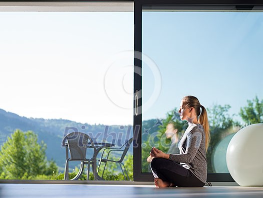 A young handsome woman doing yoga exercises on the floor of her luxury home villa