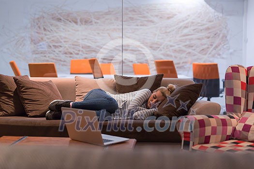 A young casual business woman sleeping on a sofa during a work break in a creative office