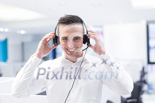 young smiling male call centre operator doing his job with a headset young smiling male call centre operator doing his job with a headset
