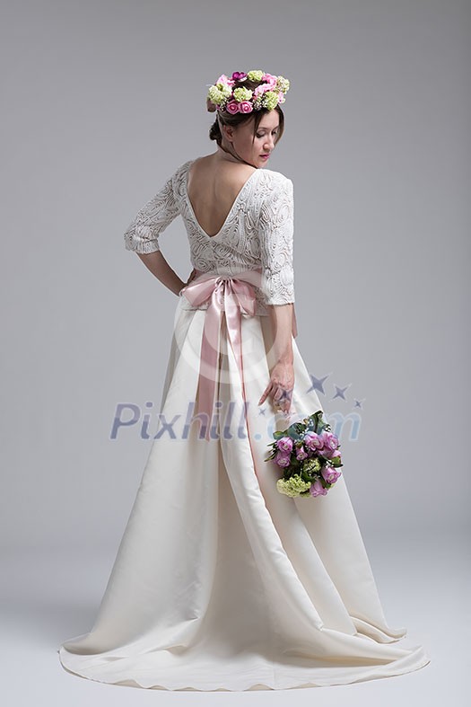 Young attractive bride with the a bouquet of flowers isolated on white background.