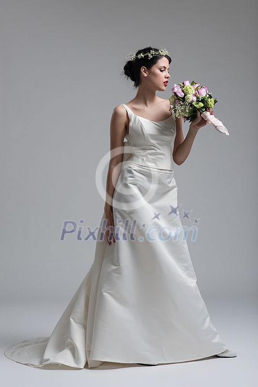Young attractive bride with the a bouquet of flowers isolated on white background.