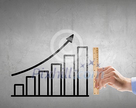 Close up of hand measuring growing graph with ruler