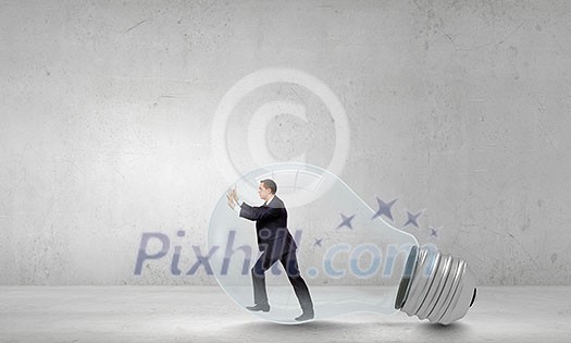 Businessman inside light bulb trying to get out