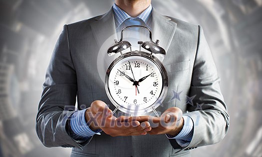 Close up of man holding alarm clock in hands