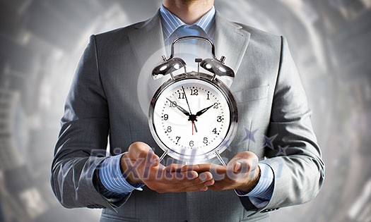 Close up of man holding alarm clock in hands Close up of man holding alarm clock in hands