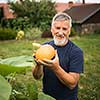 Gardener holding a pumkin in his hands - freshly harvested organic food from his permaculture garden