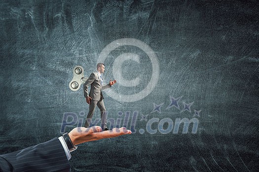 Walking businessman with wind-up key on his back. Mixed media Walking businessman with wind-up key on his back. Mixed media