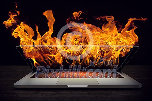 Laptop in fire flames on dark background. Mixed media