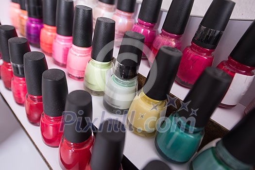 Set of different bottles of nail polish in the shelf in the beauty salon