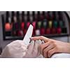 Woman hands receiving a manicure in beauty salon. Nail filing. Close up, selective focus.