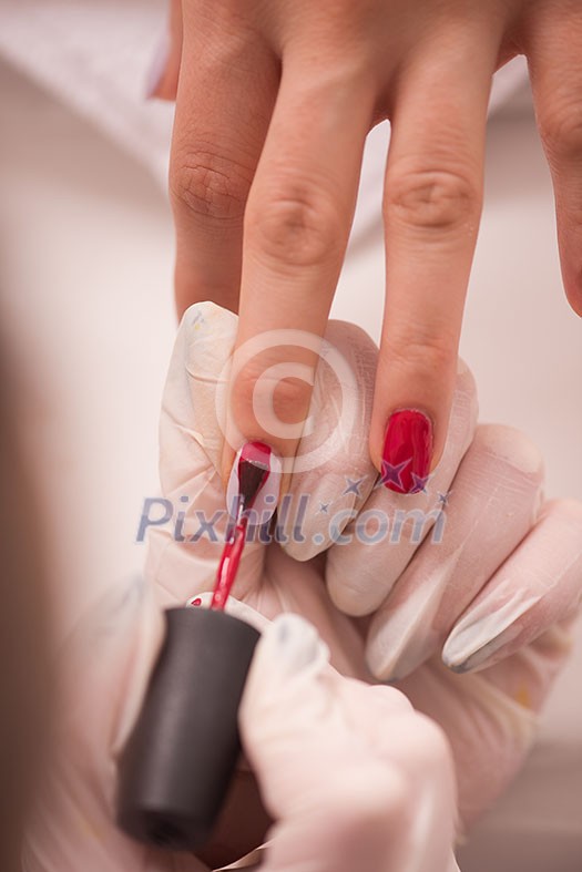 Woman hands receiving a manicure in beauty salon. Nail filing. Close up, selective focus.