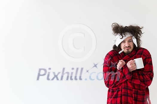 young Man with flu and fever wrapped holding cup of healing tea isolated over white