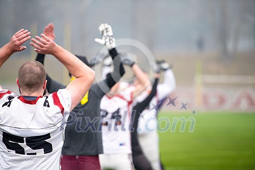 group of young american football players warming up and stretching together before a practice on the field