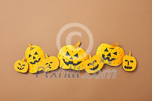 Different handcraft scary pumpkins on a brown background with space for text. Creative composition for Halloween. Flat lay Different handcraft scary pumpkins on a brown background with space for text. Creative composition for Halloween. Flat lay