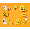 Flying paper ghosts and handcraft pumpkins in the shape of a square frame on an orange background with space for text. Layout for postcard to halloween