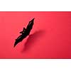 Paper flying handcraft bat presented on a red background with a pattern of shadows and space for text. Mystic Halloween layout. Flat lay