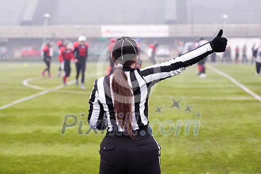 rear view of female american football referee giving signals to professional players during match on the stadium field rear view of female american football referee giving signals to professional players during match on the stadium field