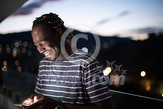 Young manl on urban city street at night texting on smartphone with bokeh and neon city lights in background Young manl on urban city street at night texting on smartphone with bokeh and neon city lights in background