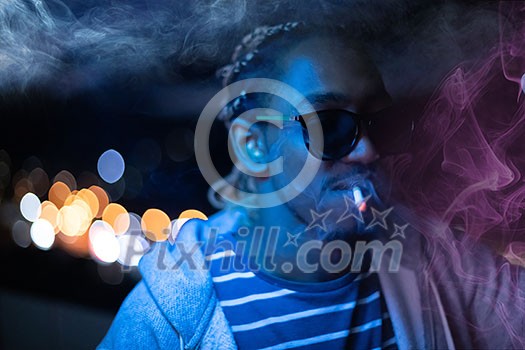 young african american man smiking cigarette with neon ligts and disco party at night young african american man smiking cigarette with neon ligts and disco party at night