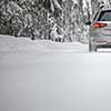 Car on a snowy winter road amid forests - using its four wheel drive capacities to get through the snow