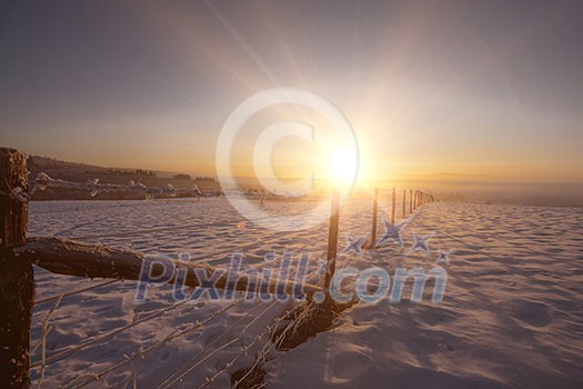 Beautiful winter landscape during sunset over snow covered field