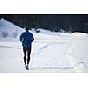 young  man jogging on snow in forest, bautiful sunny winter day. handsome sporty ahtlete man running
