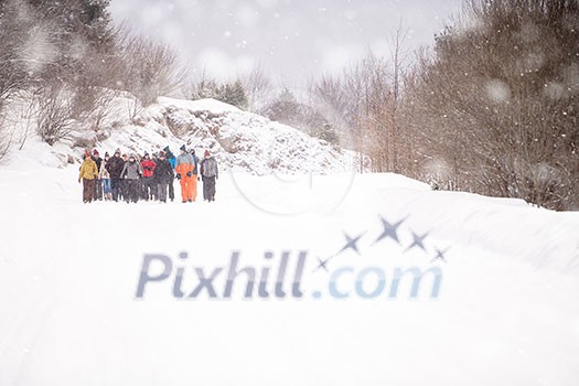 group of young business people walking through beautiful winter landscape with snowflakes around them during a team building in the mountain forest