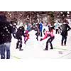 group of young happy business people having a competition in making snowmen while enjoying snowy winter day with snowflakes around them during a team building in the mountain forest