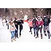 group portrait of young happy business people after a competition posing with finished snowman while enjoying snowy winter day with snowflakes around them during a team building in the mountain forest