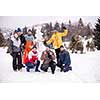 group portrait of young happy business people after a competition posing with finished snowman while enjoying snowy winter day with snowflakes around them during a team building in the mountain forest