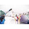 group of young happy business people after a competition measuring the height of finished snowman while enjoying snowy winter day with snowflakes around them during a team building in the mountain forest