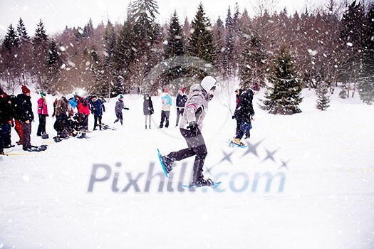 group of young happy business people having a running competition using snowshoes while enjoying snowy winter day with snowflakes around them during a team building in the mountain forest group of young happy business people having a running competition using snowshoes while enjoying snowy winter day with snowflakes around them during a team building in the mountain forest