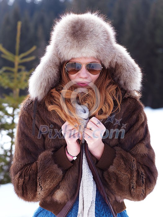 portrait of beautiful young redhair woman in snow scenery with warm hat