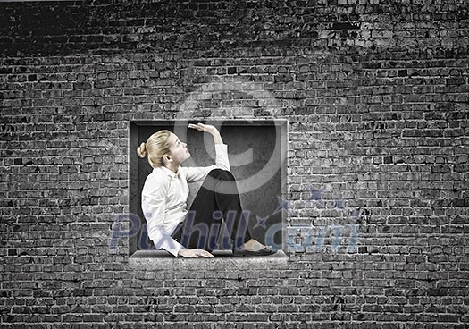 Young businesswoman trapped in stone cube in wall Young businesswoman trapped in stone cube in wall