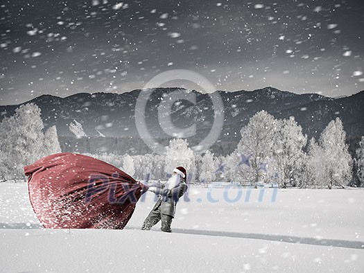 Santa Claus among snow pulling big gift bag
