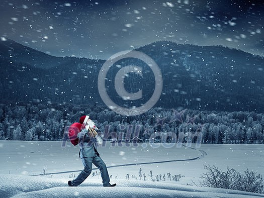 Businessman in Santa hat running with big red bag on back. Mixed media