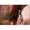 people, and relaxation concept   beautiful young woman in bath robe drinking champagne at spa over holidays lights background