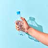 Empty plastic bottle crushed by hand on a pastel blue background with transparent shadows. Place for text. Ecological problem of environmental pollution.