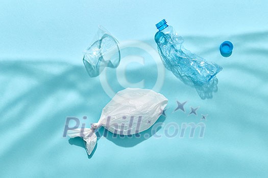 Fish in polythene bag and plastic bottles are floating under water from shadows on a pastel blue background, copy space. Ecological problem of pollution world ocean.