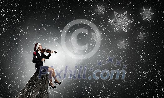 Woman in formal suit and Santa hat playing violin