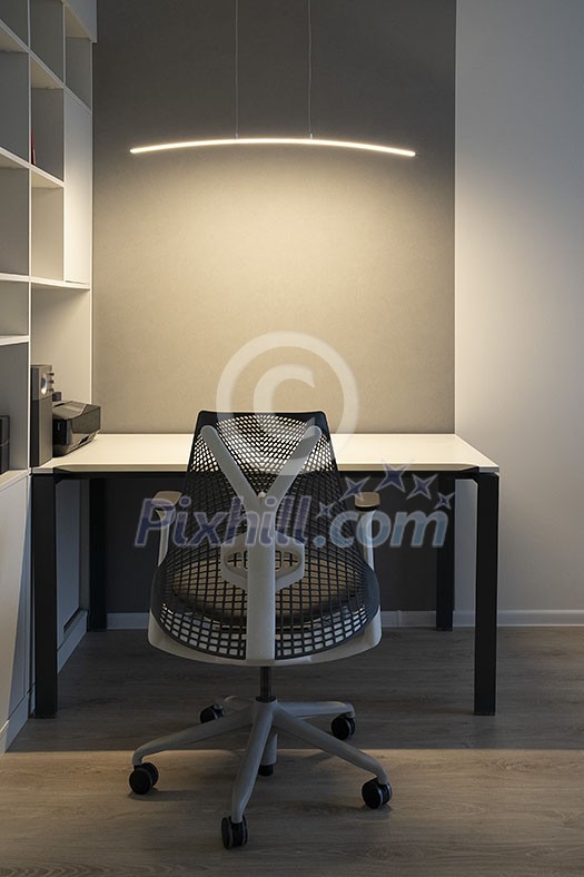 Well-organized ergonomics of workspace in the modern office. Computer table, orthopaedic chair and soft lighting above desk. Well-organized ergonomics of workspace in the modern office. Computer table, orthopaedic chair and soft lighting above desk.