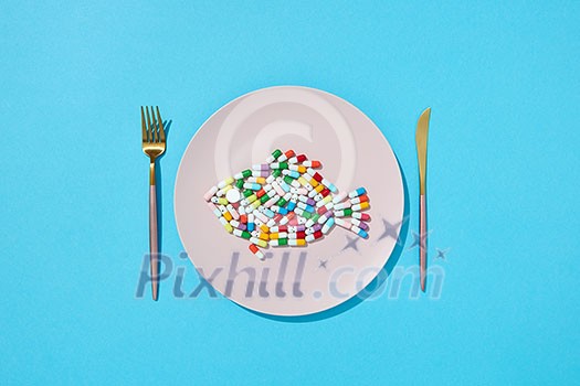 Many different pills and supplements as food on round white plate with fork and knife. Diet pills and supplements for dieting concept. Top view. Many different pills and supplements as food on round white plate with fork and knife. Diet pills and supplements for dieting concept. Top view.