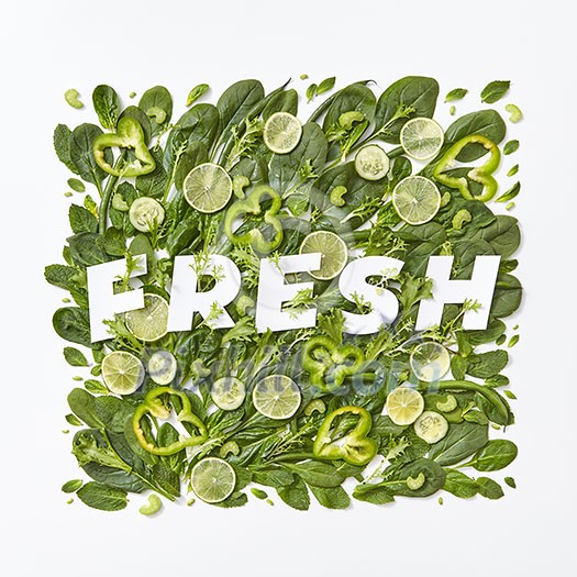 Healthy variety of green vegetables cabbage, spinach,flower petals, asparagus pieces pepper on a gray background with a paper inscription fresh on a gray background with copy space. Flat lay