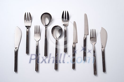 A variety of spoons, knives and forks on a gray background with space for text. Vintage set. Flat lay