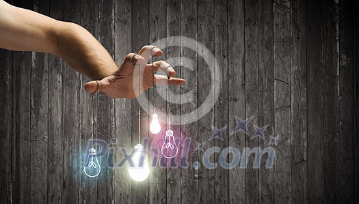 Close up of human hand and light bulbs hanging on finger Close up of human hand and light bulbs hanging on finger