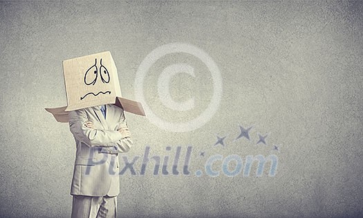 Businessman wearing carton box with drawn emotions on head Businessman wearing carton box with drawn emotions on head